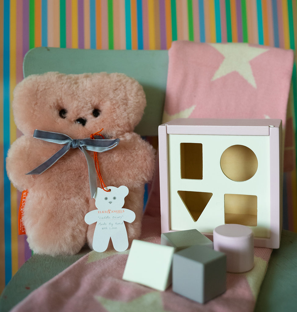 pink sheepskin bear with wooden toy shape sorter and cotton star blanket in pink